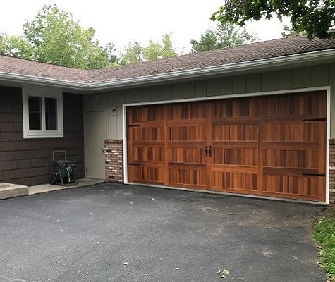 Wooden carriage house garage door on green ranch-style house