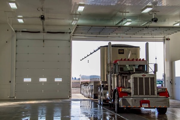 Semi-truck pulling into warehouse garage with steel roll-up garage doors