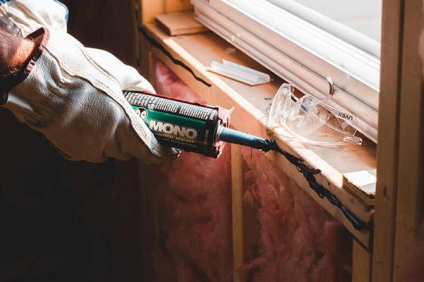 Contractor applying weatherproof sealant to window frame